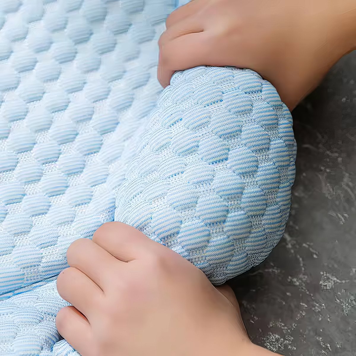 Close-up of a textured blue mat with hands on a dark surface